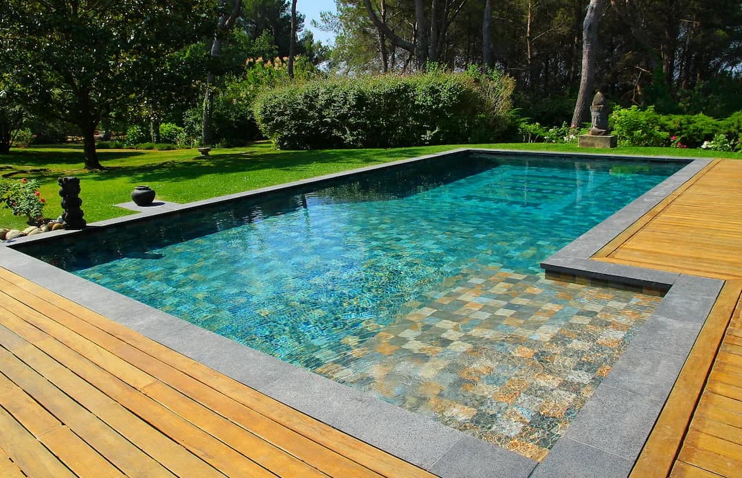 Piscine style balinais avec eau émeraude et margelles en travertin à Le Plan proche de Montberaud